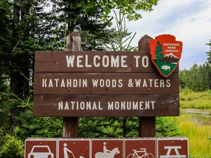 Katahdin Woods & Waters National Monument Camping — A close up of a National Park welcome sign on the way to Sandbank Stream Campground. It is wooden and says "Welcome to Katahdin Woods and Waters National Monument"