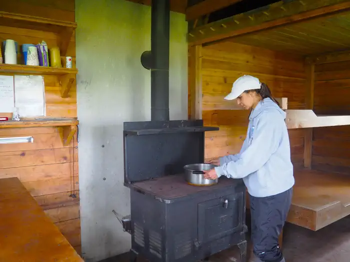 Gut Island 1 Cabin — A woman cooking on stove in Gut Island cabin 1