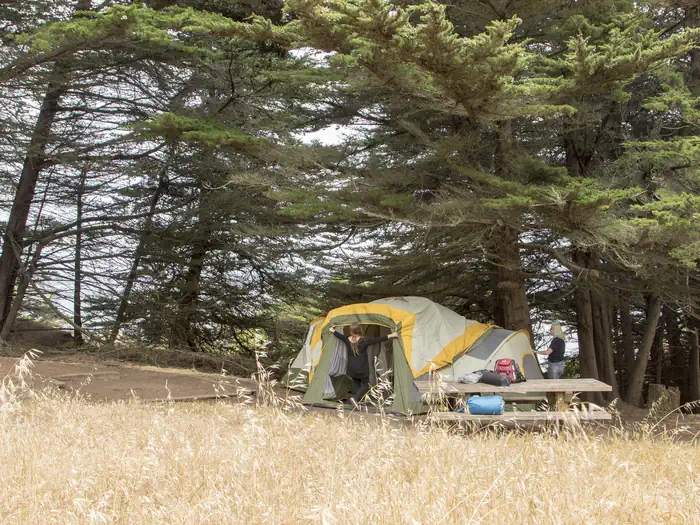 BICENTENNIAL CAMPGROUND — Two people set up a large tent near a picnic table at Site 3.