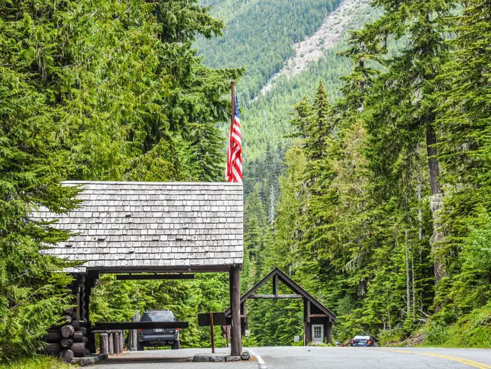White River Campground — White River Entrance Station with wooden cabins on a highway with one building flying an American flag