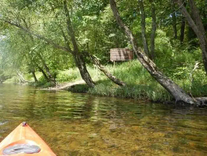 Alosa Campsites — Yellow kayak on river with trees in the background