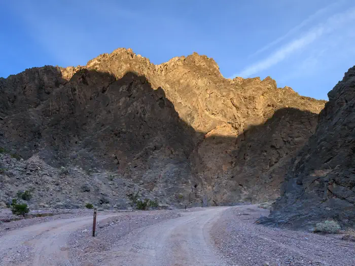 Death Valley Backcountry Roadside Camping — Gravel dirt road with a parallel roadside campsite surrounded by dark canyon walls.
