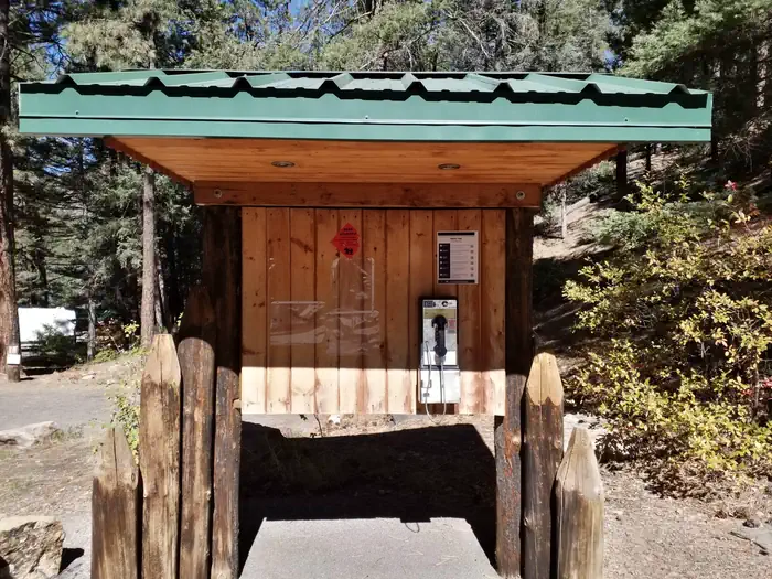 Black Canyon Campground (santa Fe National Forest, Nm) — A payphone located underneath a wooden kiosk with a green metal roof.