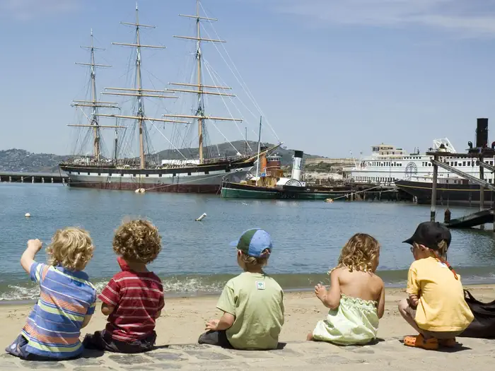 Aquatic Park Cove, Black Point Overnight Anchoring, Sailing Vessels Only (auxiliary Engine Ok) — Five young children sit on the beach on a July afternoon at Aquatic Park Cove, San Francisco.