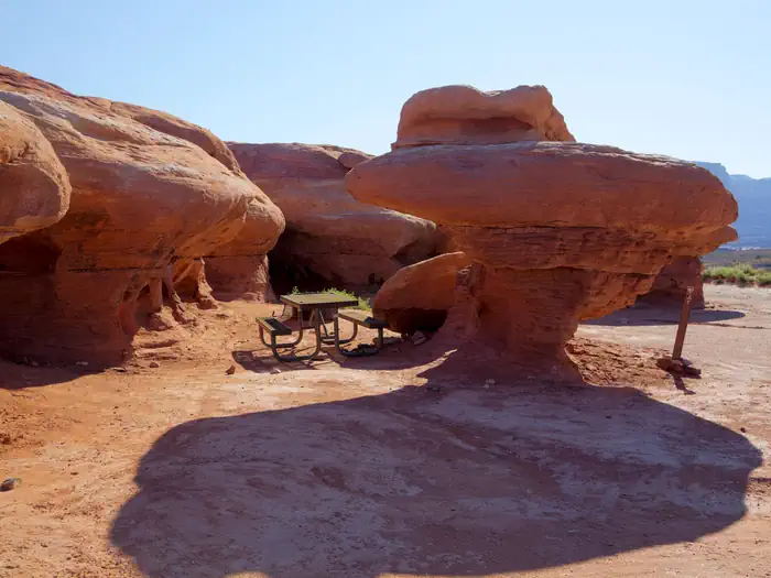 Hamburger Rock Campground — A picnic table underneath unique, overhanging red rock features.