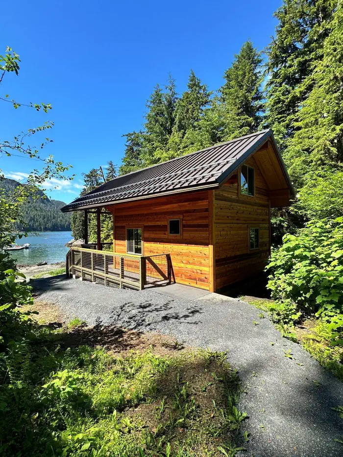 Anan Bay Cabin — View of the side and back of Anan Bay Cabin with bay and boats in background.