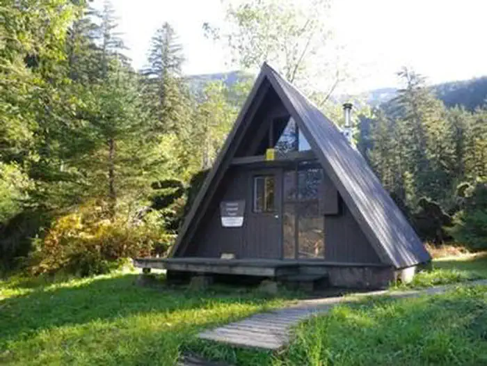 Garnet Ledge Cabin — A-frame Garnet Ledge Cabin with wooden walkway and trees with grass in front