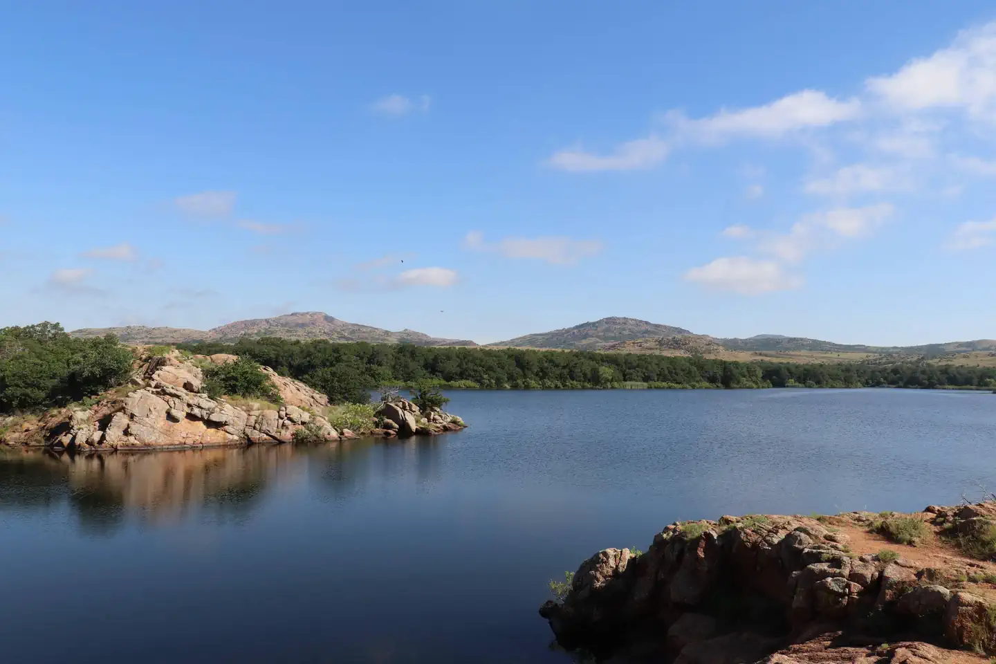 Camp Doris — The Wichita Mountains line the horizon beyond the pink granite shore of Quanah Parker Lake.