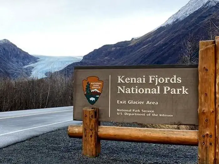 Kenai Fjords National Park Cabins — Kenai Fjords entrance sign on the road with Exit Glacier in the background.