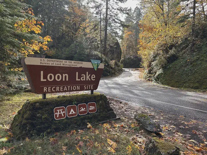 Loon Lake Recreation Site — View of Loon Lake Recreation Site entrance sign in the foreground with the entrance road in the background.