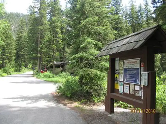 Swan Creek Campground — Swan Creek Entrance - Information board, road, RV and pine trees