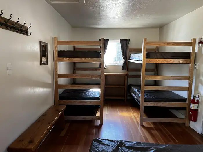 Cowpuncher Guard Station β Bedroom showing double bed, two sets of bunkbeds and bench.