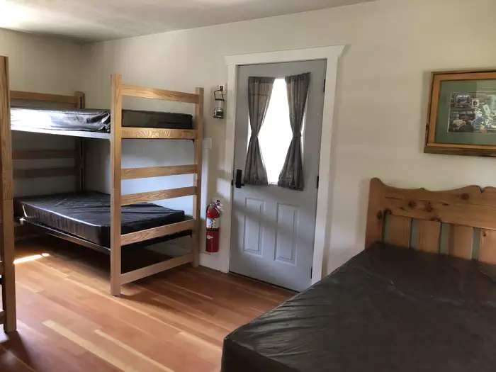 Cowpuncher Guard Station β Bedroom is furnished with two sets of bunkbeds and one double bed.