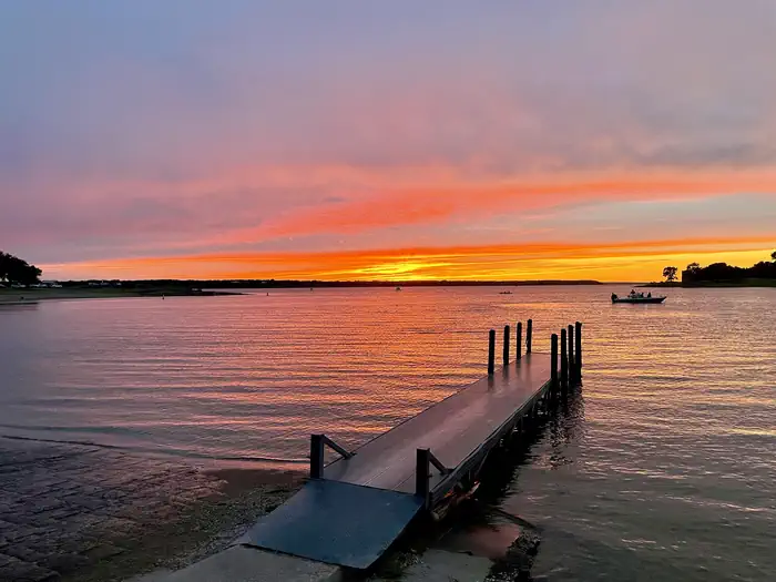 Whitney Lake — Sunset silhouetting two boats with boat ramp and courtesy dock in the foreground