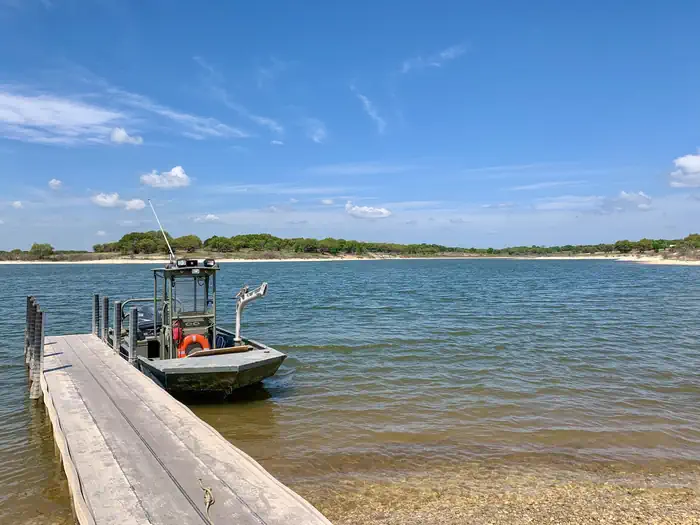 Whitney Lake — Park Ranger boat at the end of the courtesy dock with blue skies and clear water.