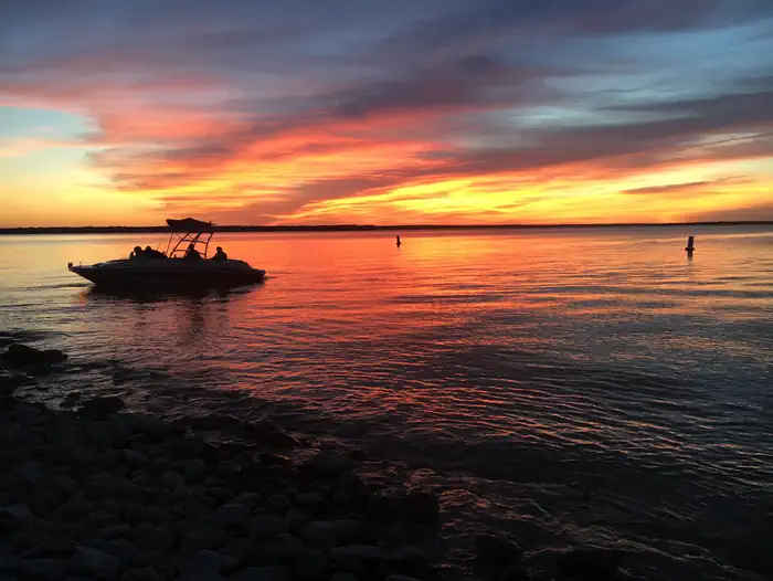 Whitney Lake — Wake boat silhouetted by sunset from beach at McCown Day Use Park