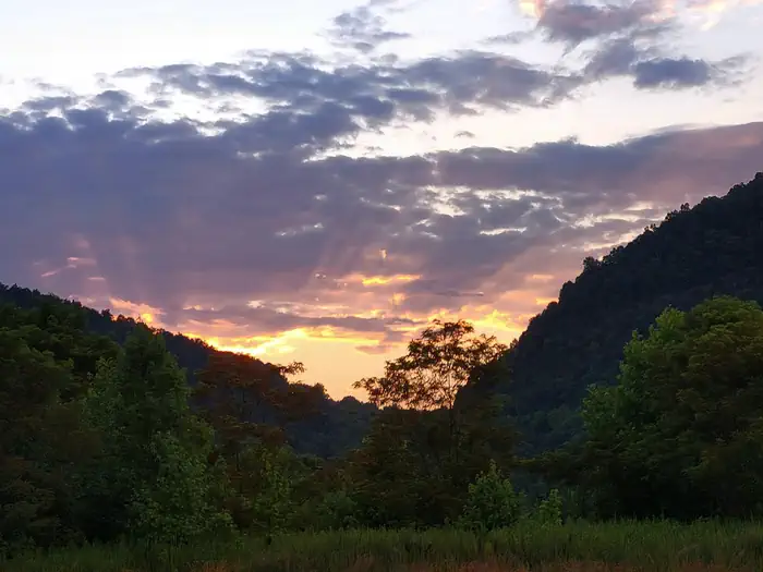 Cumberland Gap National Historical Park — The sun rises over a V-shaped notch in a forested mountain range.