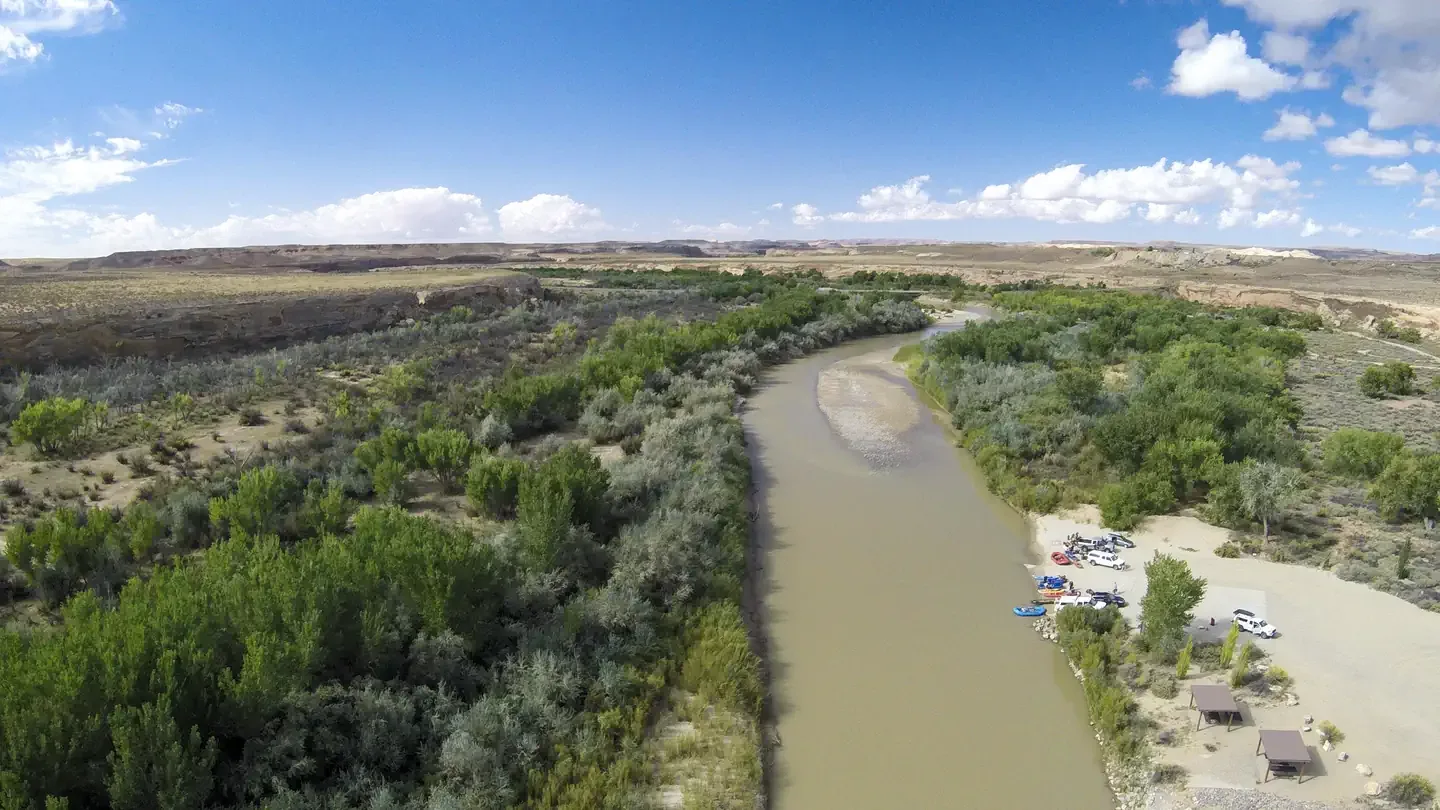 BLM Sand Island Campground: An aerial view of the San Juan River line with green cottonwood trees and the Sand Island boat launch area.