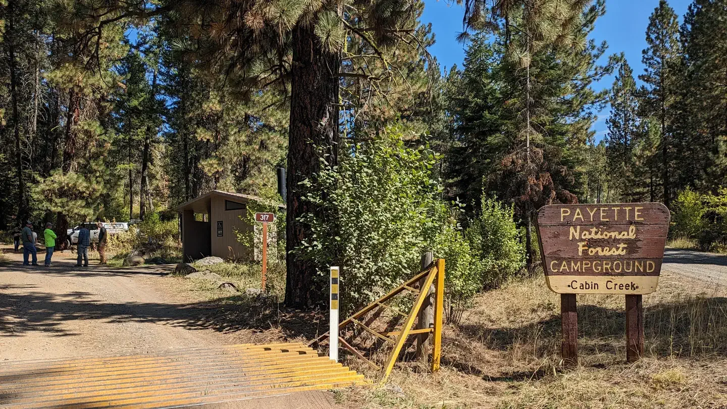 Cabin Creek Campground: Sign at entrance to campground with tall conifer trees.