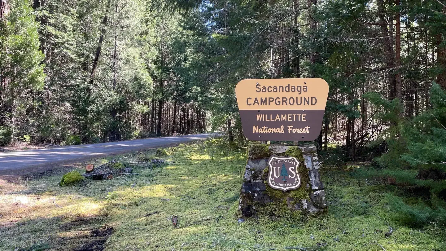 Sacandaga Campground: A cream and brown sign on a rock pedestal. The sign says " Sacandaga Campground".