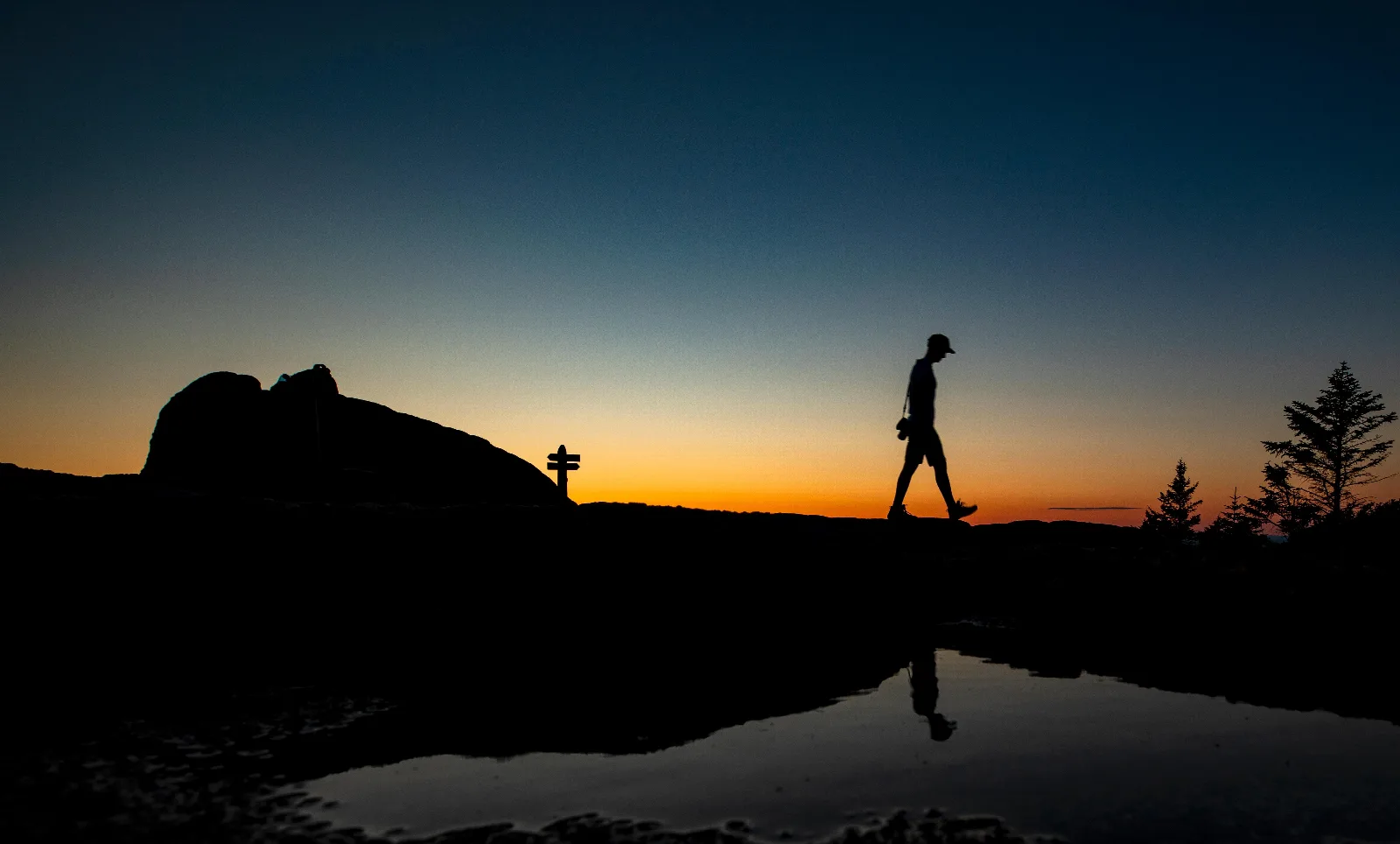 Silhouette of a hiker walking along a ridgeline at sunset