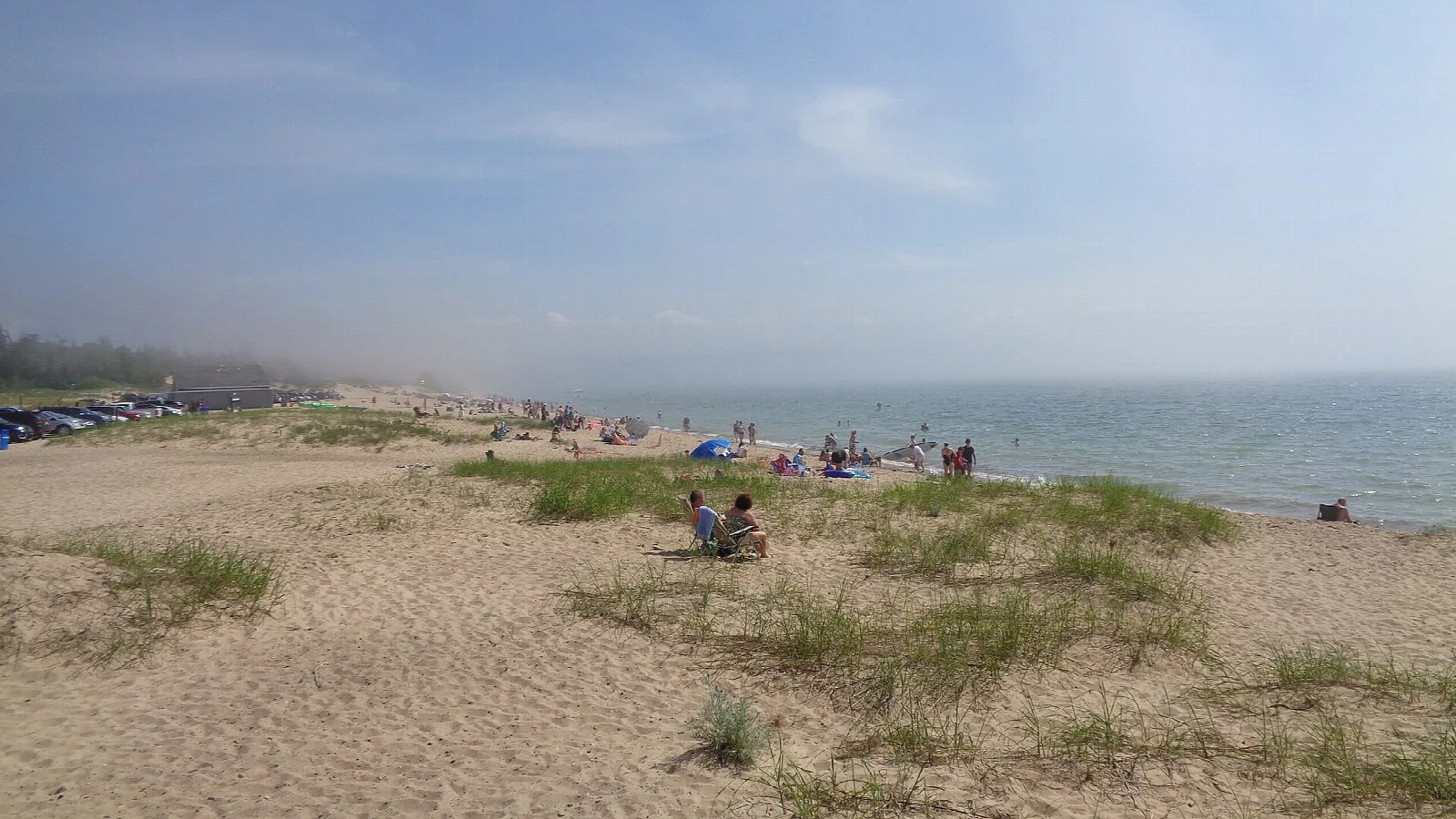 Sandy beach with dune grass and people along the Lake Michigan shore