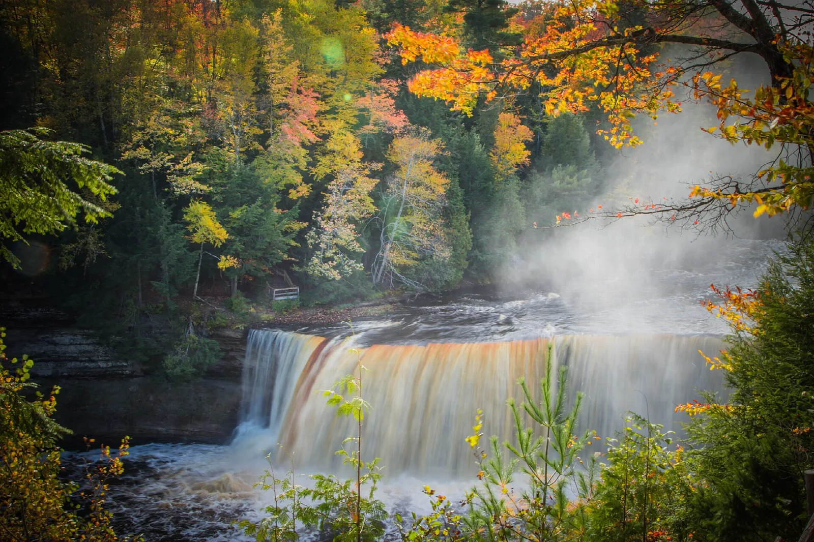 Waterfall with mist, framed by orange and yellow fall leaves