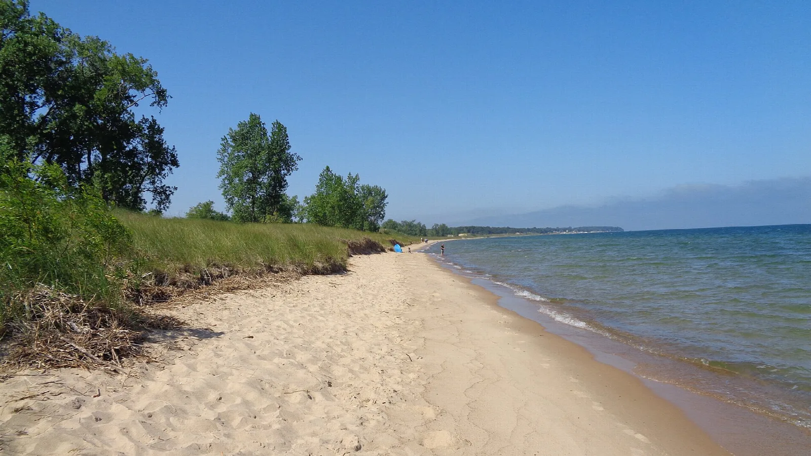 Pebbly sand beach with blue Lake Huron water and a distant shoreline