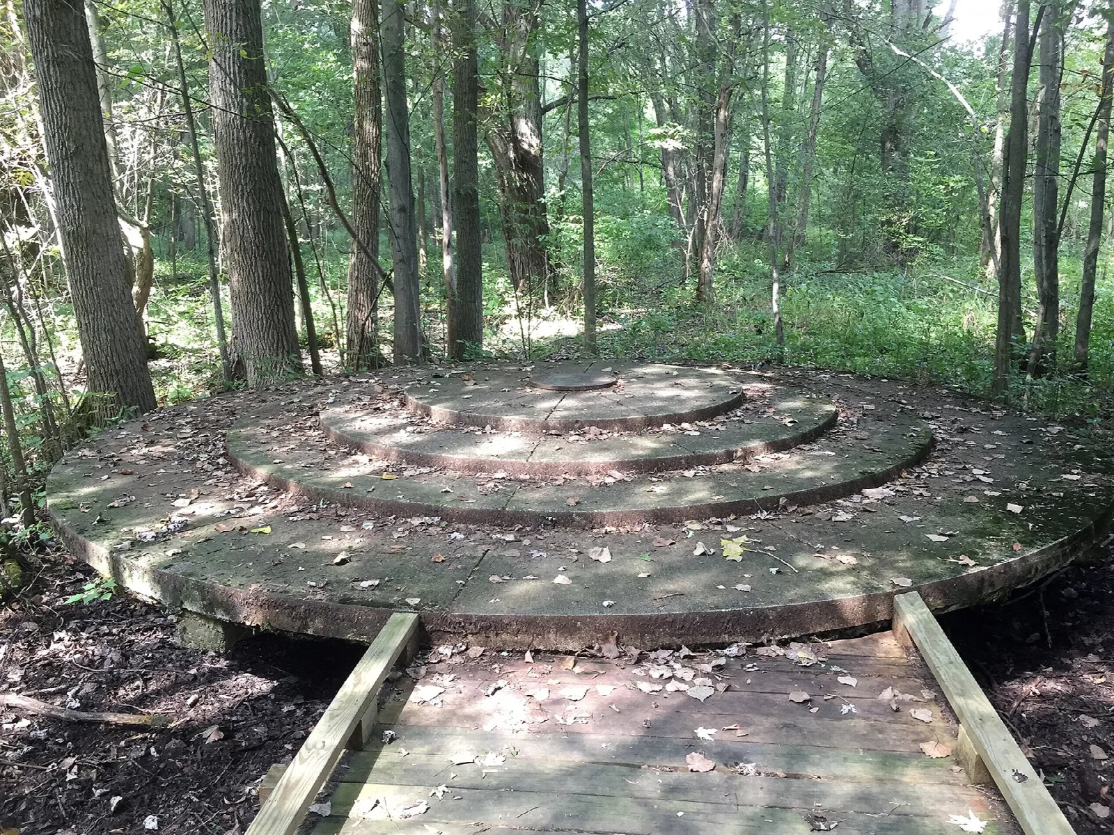 Round stepped wooden platform reached by a boardwalk in the woods