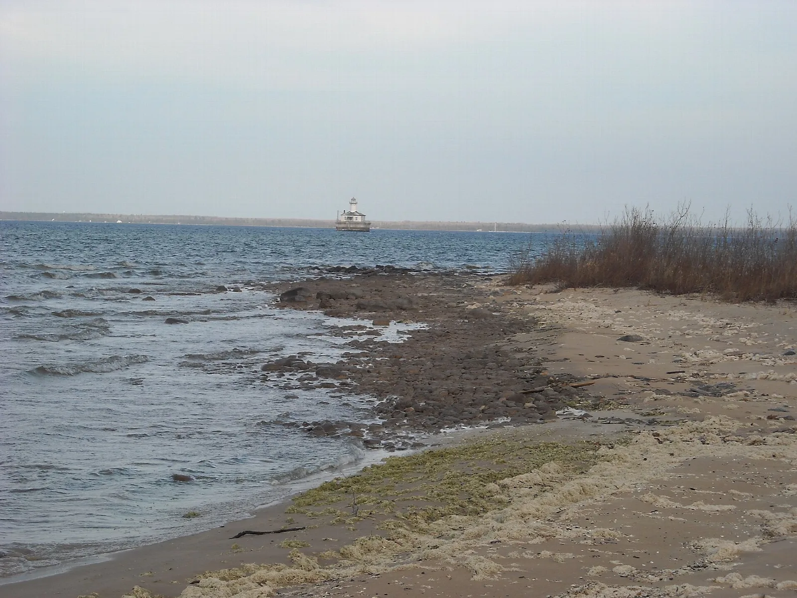 Sandy Lake Huron shoreline with a small lighthouse far out on the water