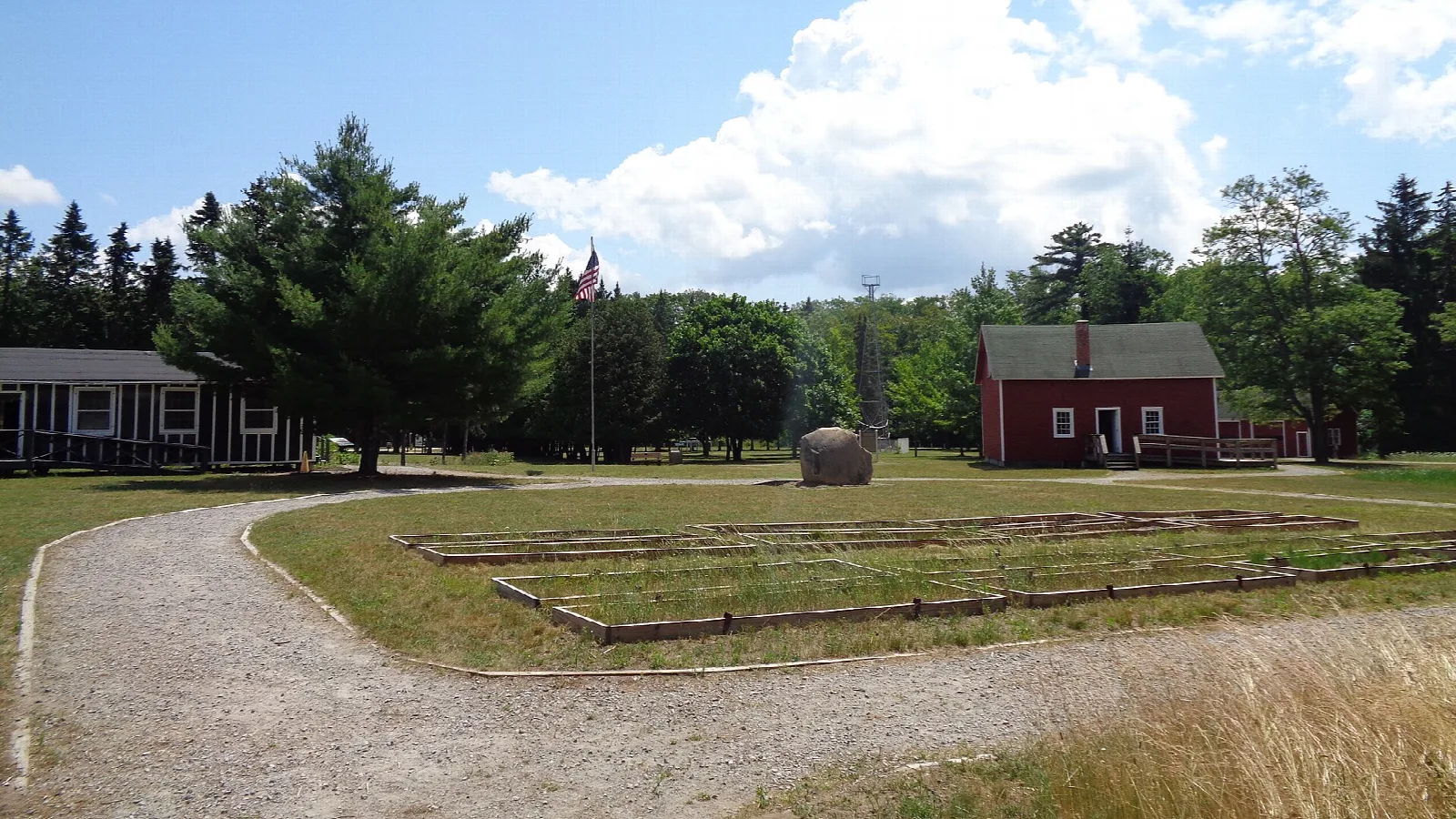 Red museum building and lawn among pine trees