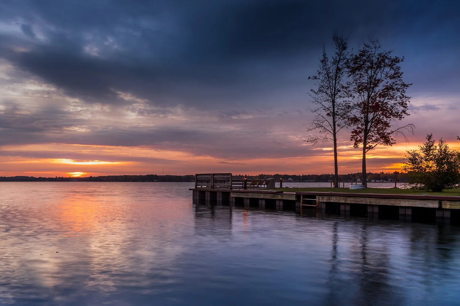 Sunset over a lake with a fishing pier and trees