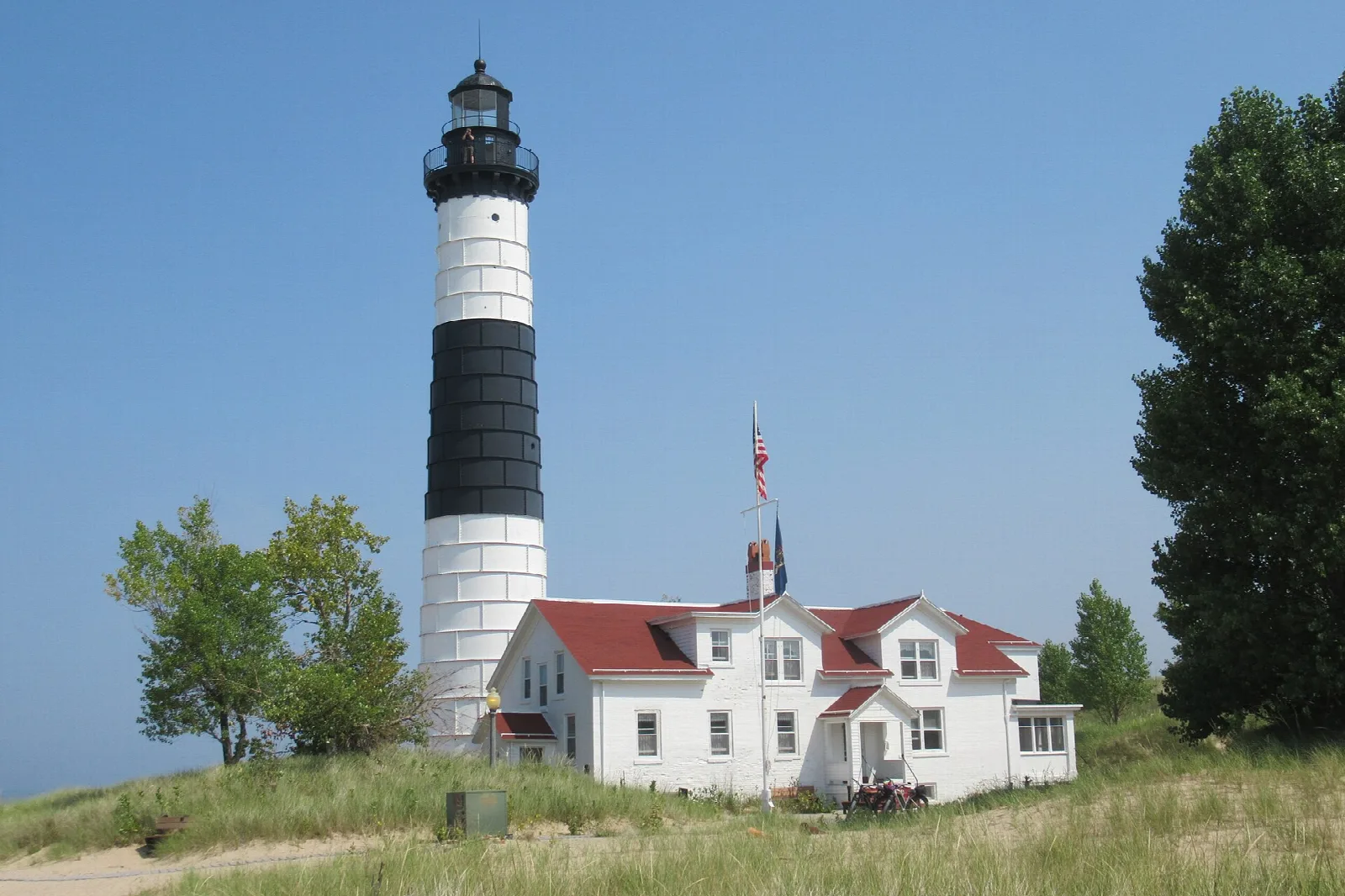 Black and white striped lighthouse above a grassy dune