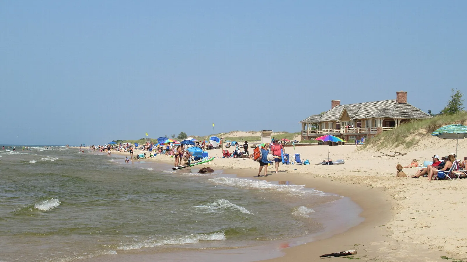 Lake Michigan beach with people, umbrellas and a beach house on the dune