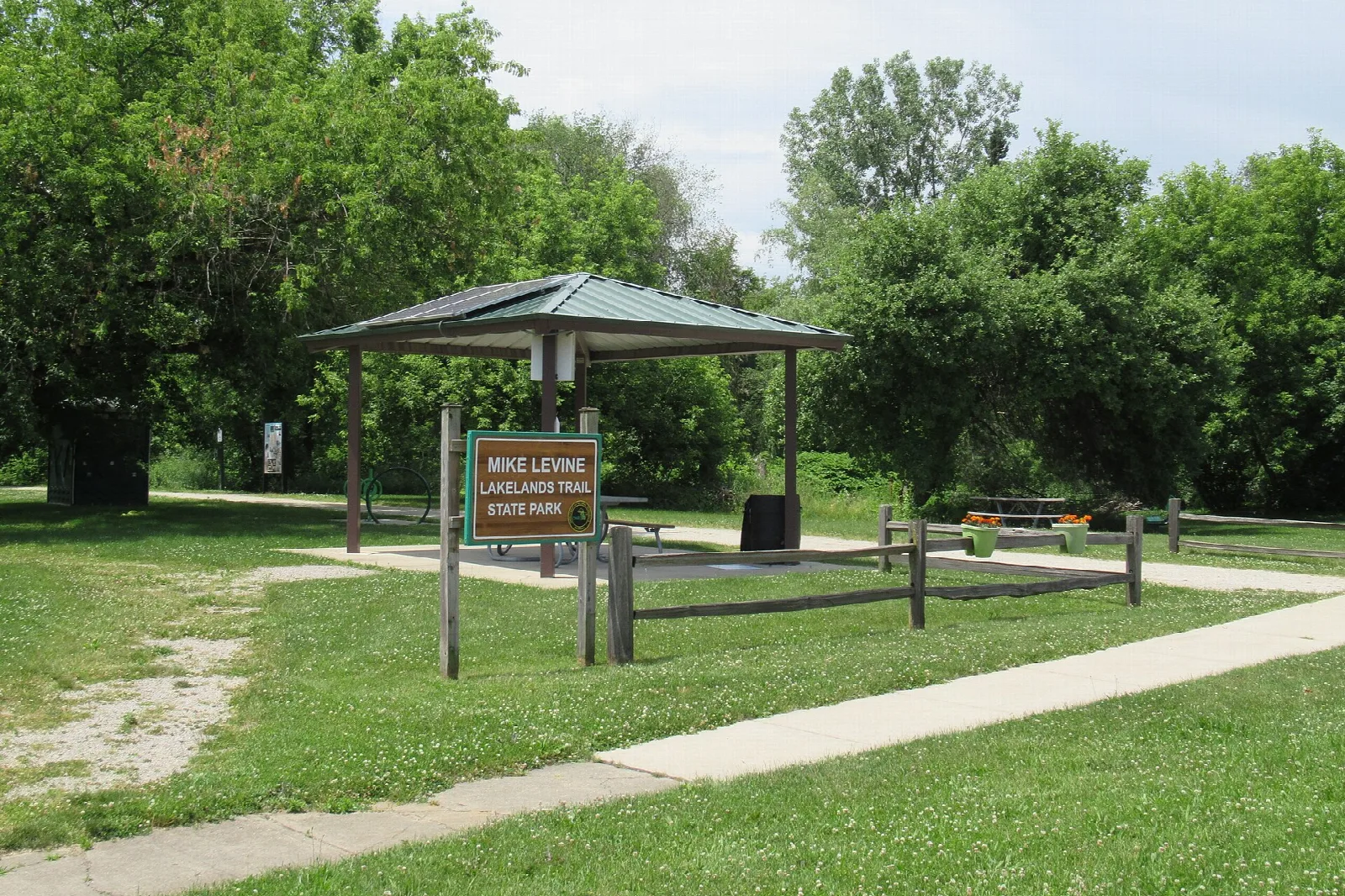 Trail shelter and sign beside a path under green trees