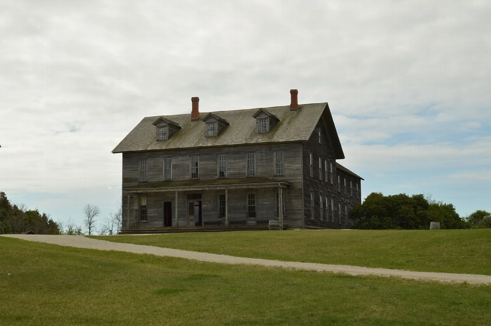 Weathered two-story wooden building on a grassy lawn