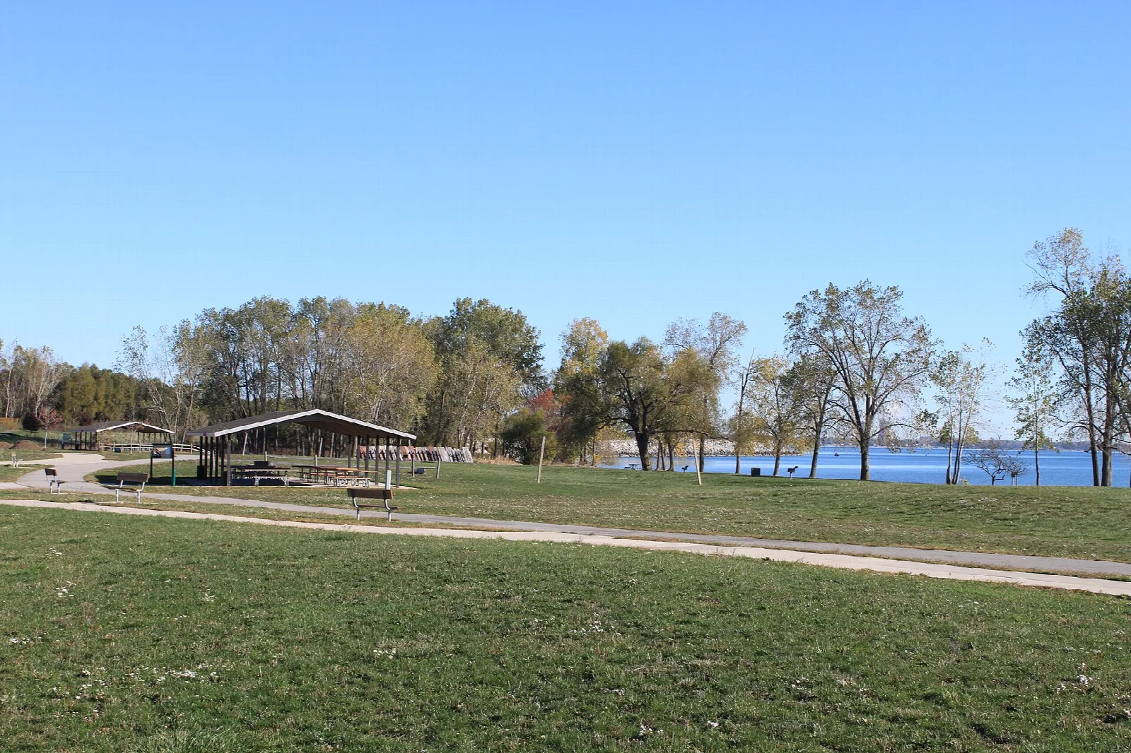 Grassy picnic area with a shelter and lake in the distance