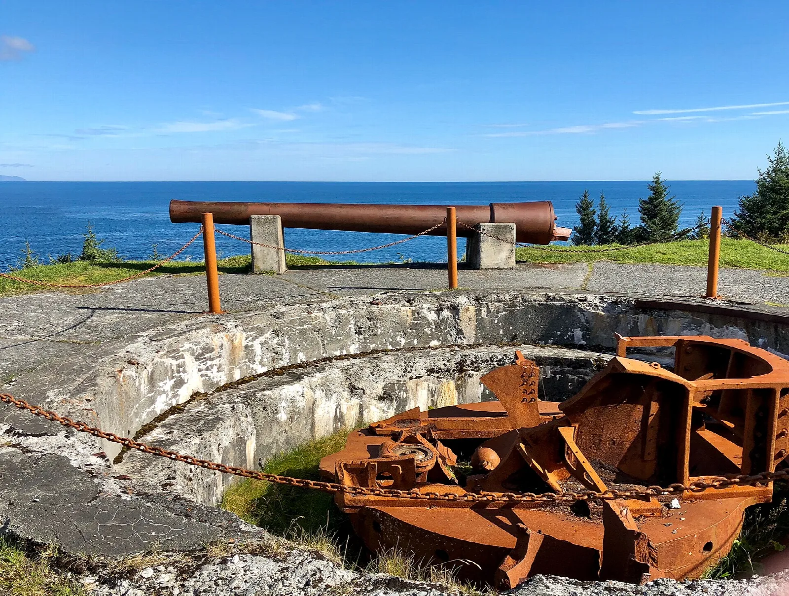 Old gun barrel on a concrete emplacement above blue ocean