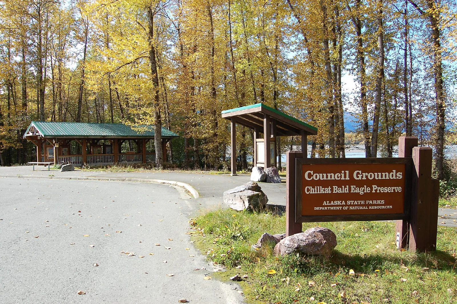 Viewing shelters and a gravel pullout among yellow fall trees beside a park sign