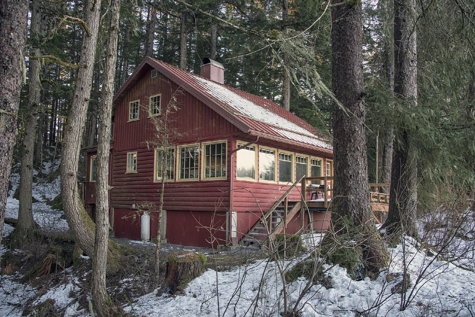 A red cabin with a long roof in snowy forest