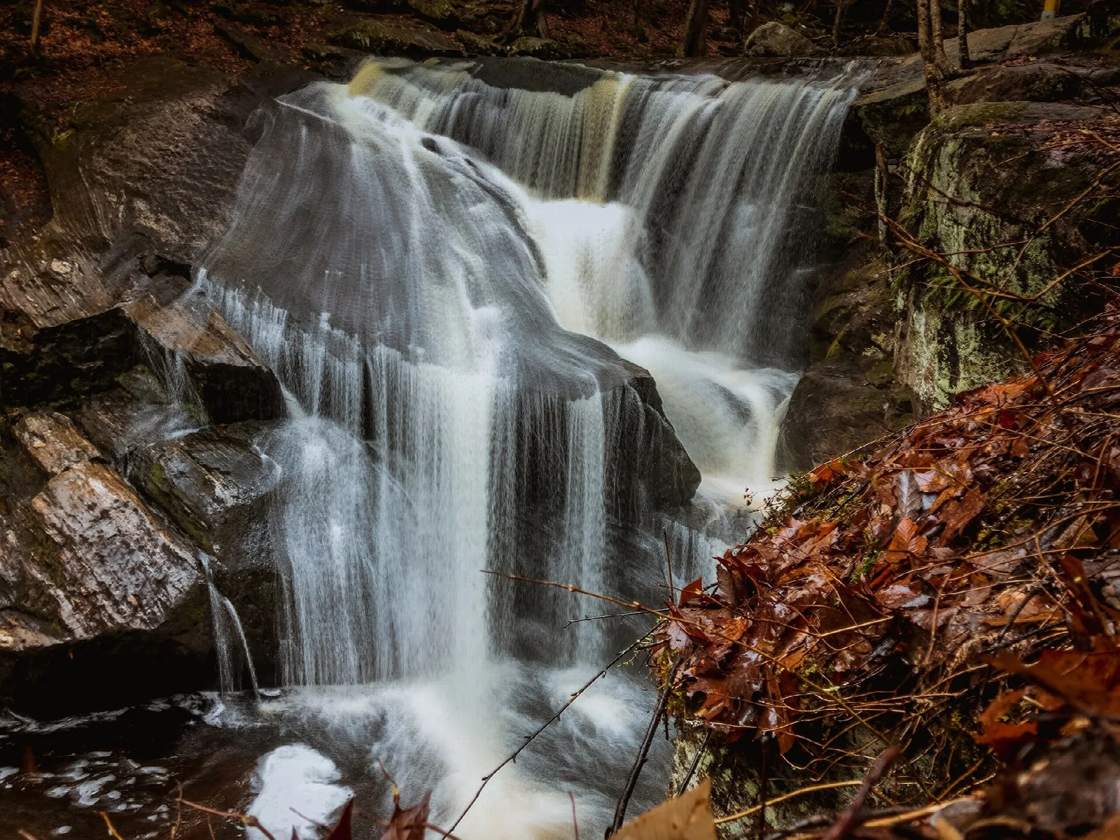 A tall waterfall pouring over dark layered rock