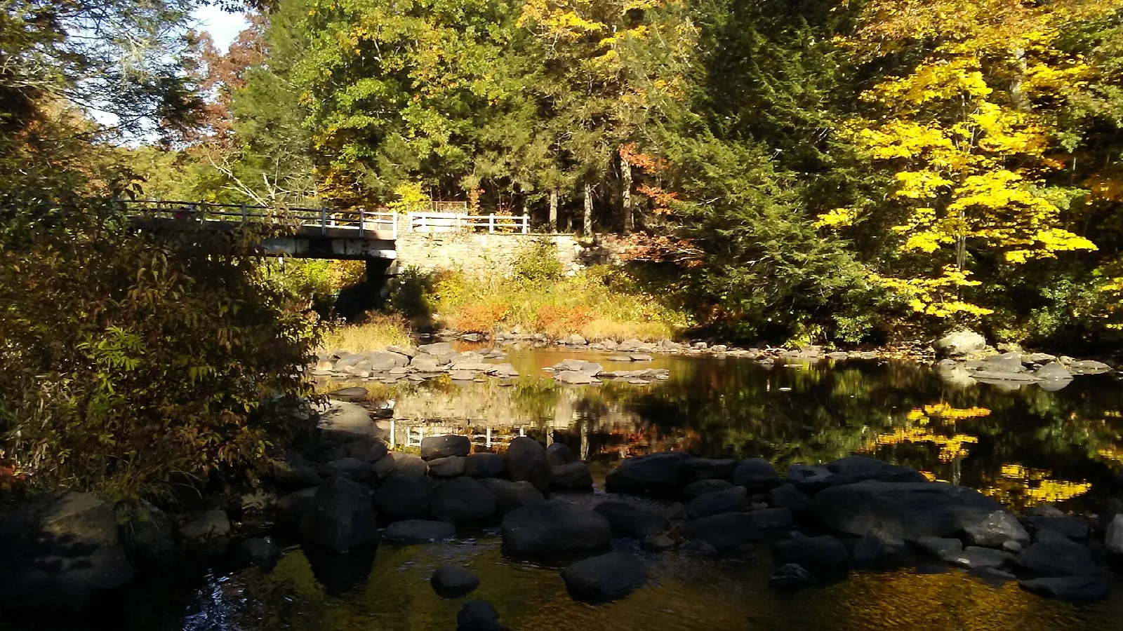A river with a footbridge among colorful autumn trees