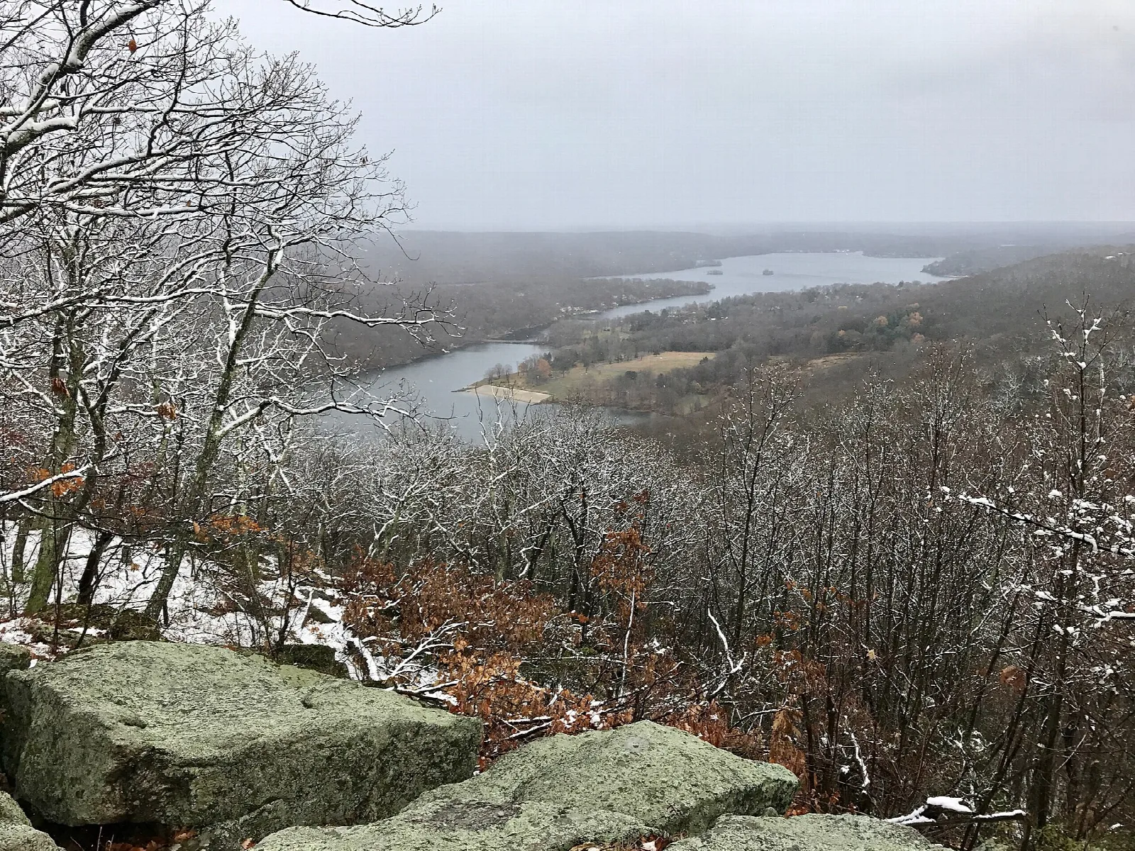 A snowy view over a bay of Candlewood Lake from a rocky overlook