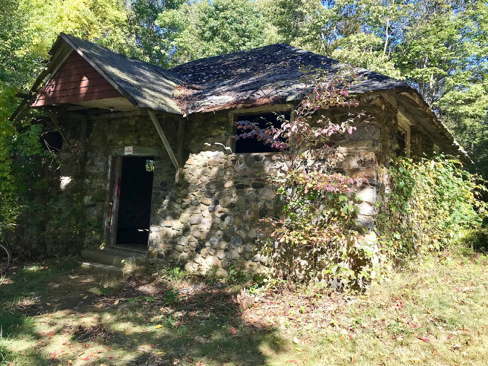 A small stone building with a peaked roof among trees