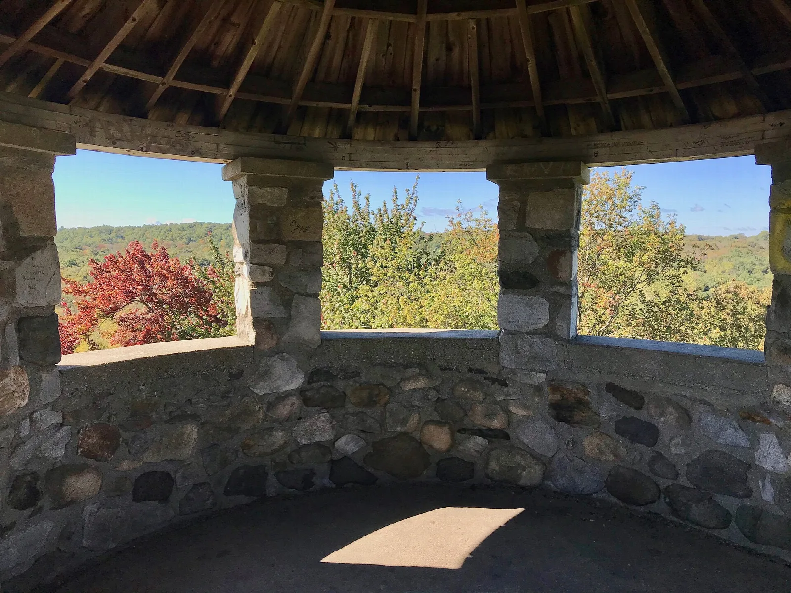 A stone tower room with open arched windows looking out at autumn trees