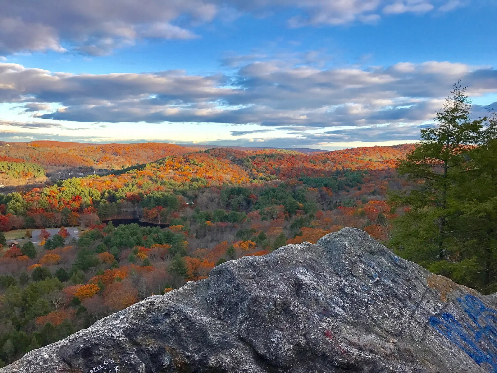 A rock ledge looking out over autumn-colored hills under a cloudy sky