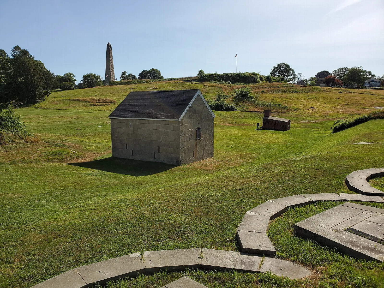 Grass-covered ramparts with a stone building and a tall obelisk in the distance
