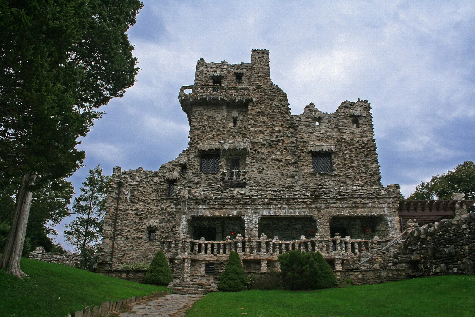 Stone castle with turrets behind a lawn and cloudy sky
