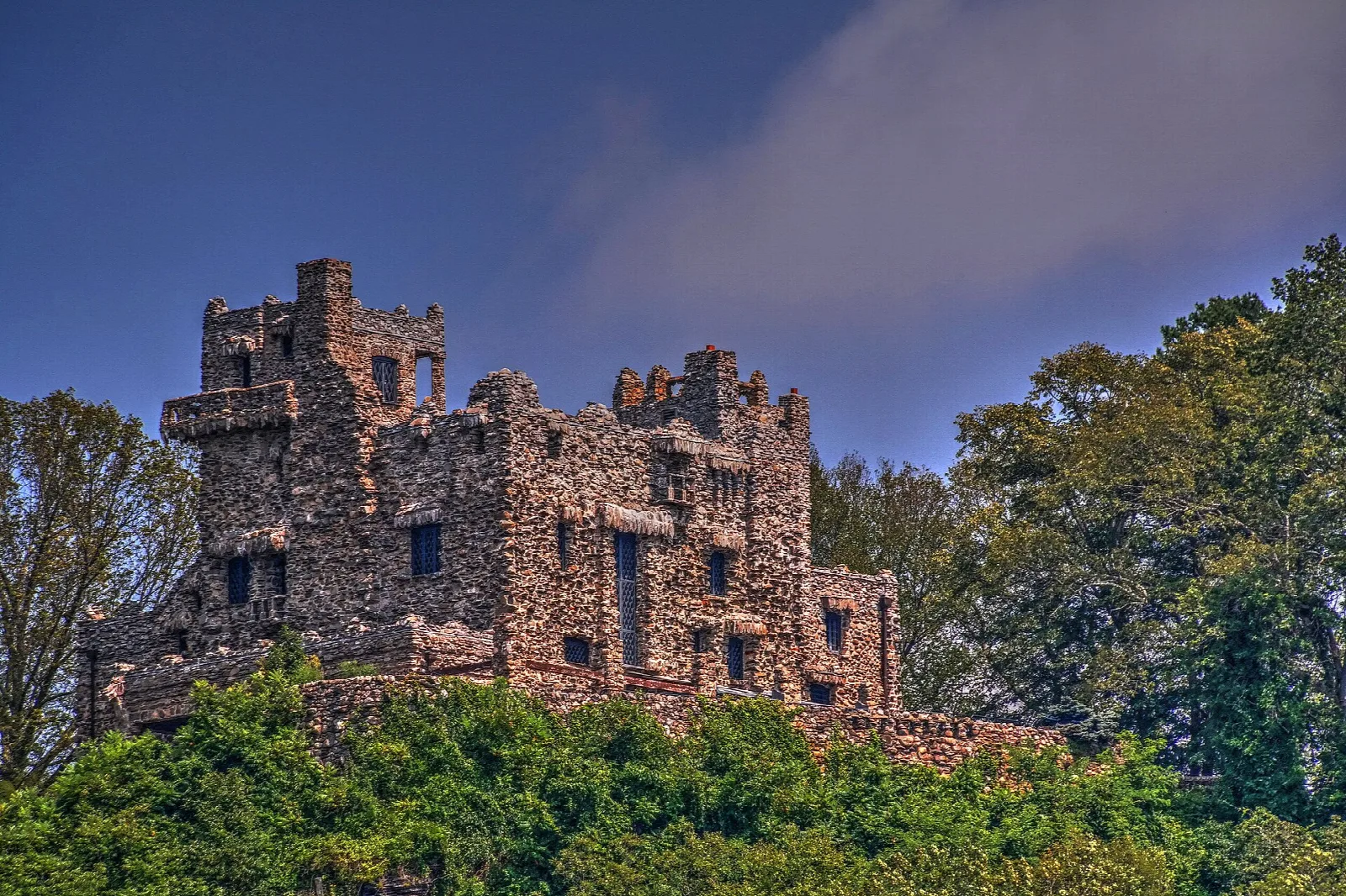 Stone castle above green trees at dusk