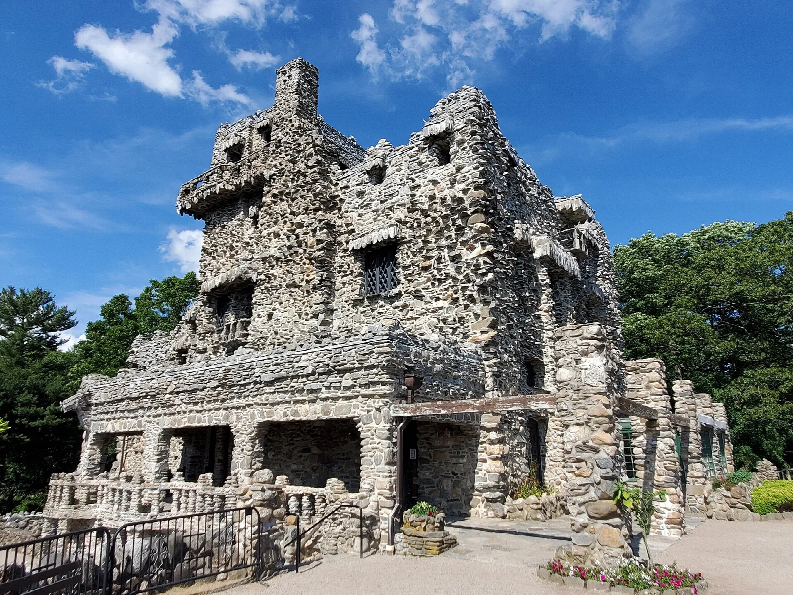 Rough stone castle with a covered porch and railing in sunshine